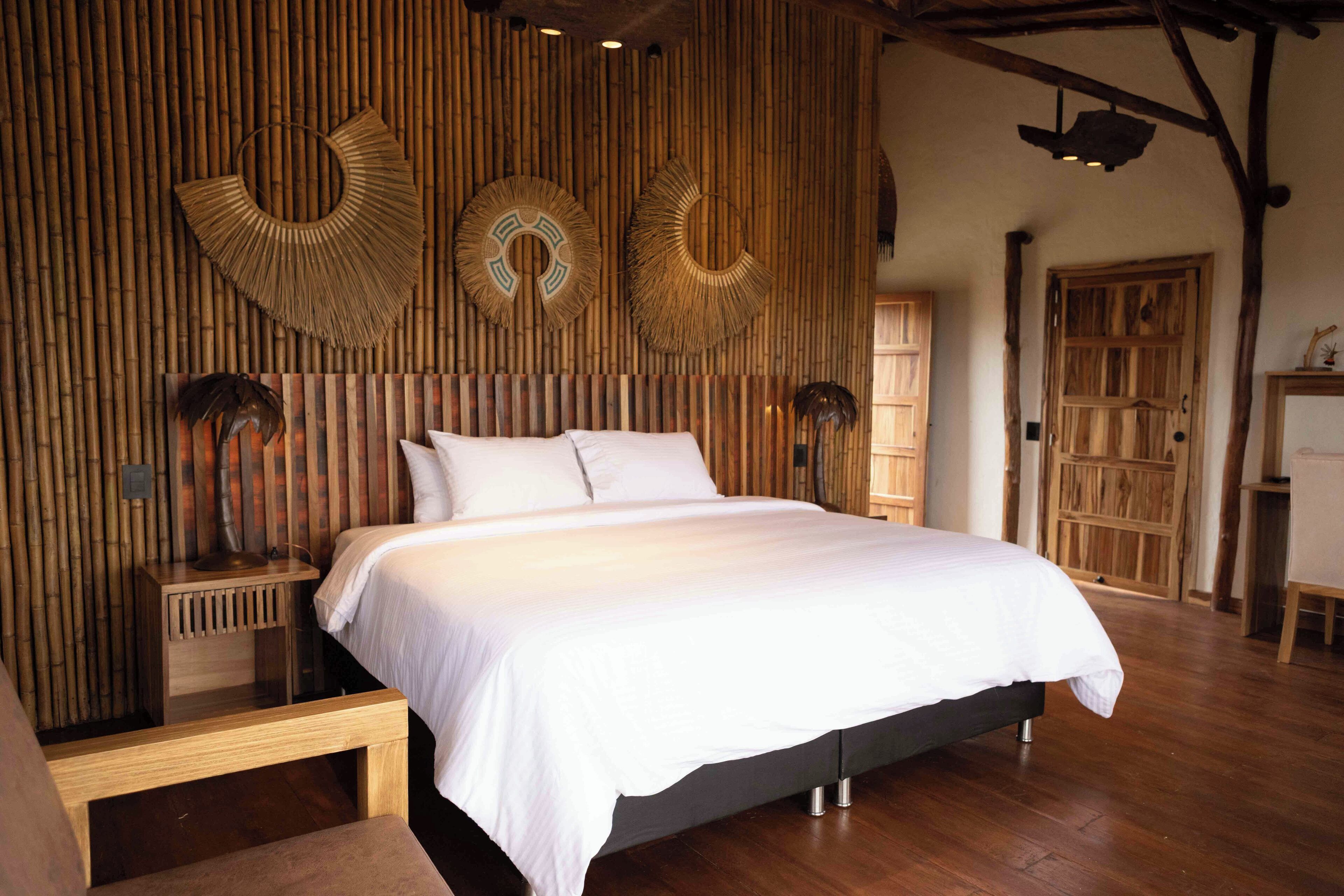 A bedroom with a large bed, wooden walls, and a rustic wooden door.