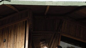 A wooden staircase leading to a covered outdoor area with bamboo walls.