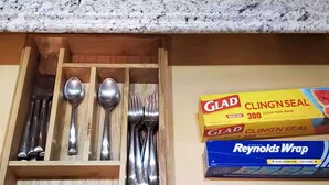 Un tiroir de cuisine contenant des ustensiles et deux boîtes de film alimentaire.