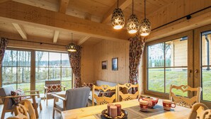 Un intérieur en bois avec une table à manger, des chaises et des luminaires suspendus.