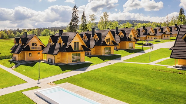Une rangée de chalets en bois avec un espace piscine à usage commun.