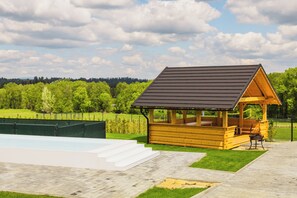 Un pabellón de madera con techo inclinado, una piscina y una zona de patio empedrada.