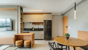 Una cucina moderna con forno integrato, frigorifero e zona pranzo con tavolo rotondo e due sgabelli.