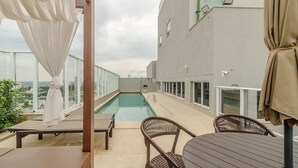 Area piscina sul tetto con vista sulla città, zona relax coperta e un edificio con un cartello che riporta 'SAIDA'.