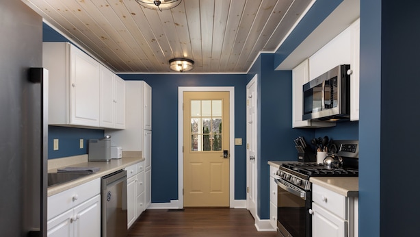 A kitchen with white cabinets, a stove, a microwave, and a door with a window. - Convenient location for adventures in the Adirondacks! (Warrensburg)