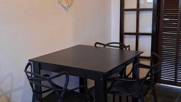 Uma área de refeições com uma mesa de madeira escura, quatro cadeiras e três plantas fixadas na parede.