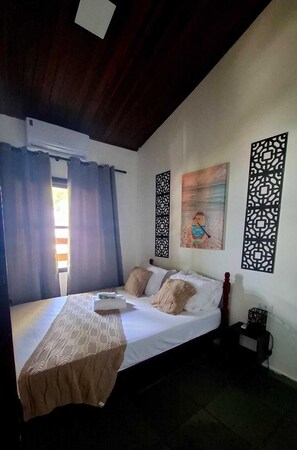 Een slaapkamer met een bed, gordijnen, een wandairconditioner, decoratieve panelen en een schilderij.
