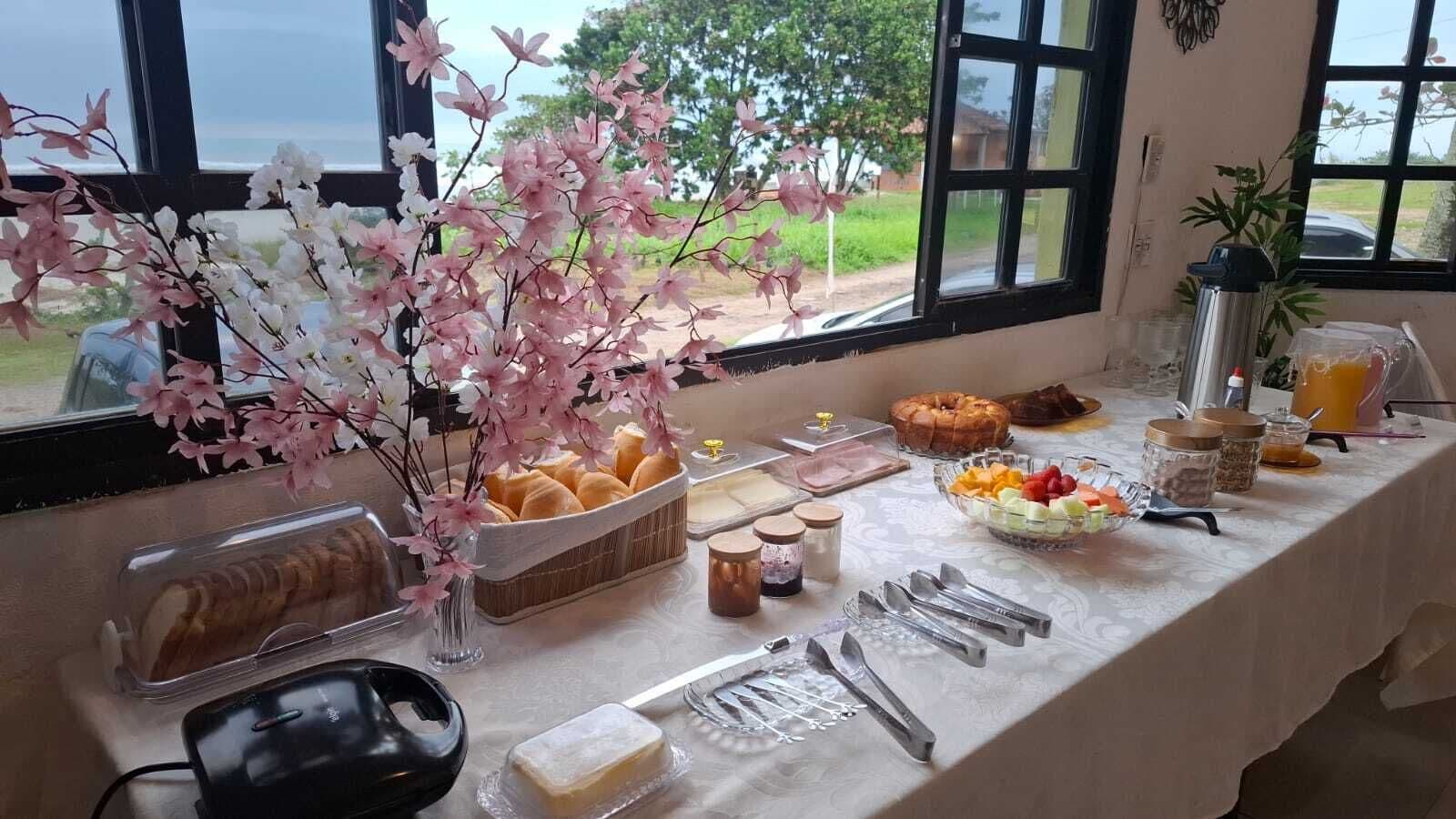 Un bufé de desayuno con diferentes alimentos, un jarrón de flores y vistas al exterior a través de una ventana.