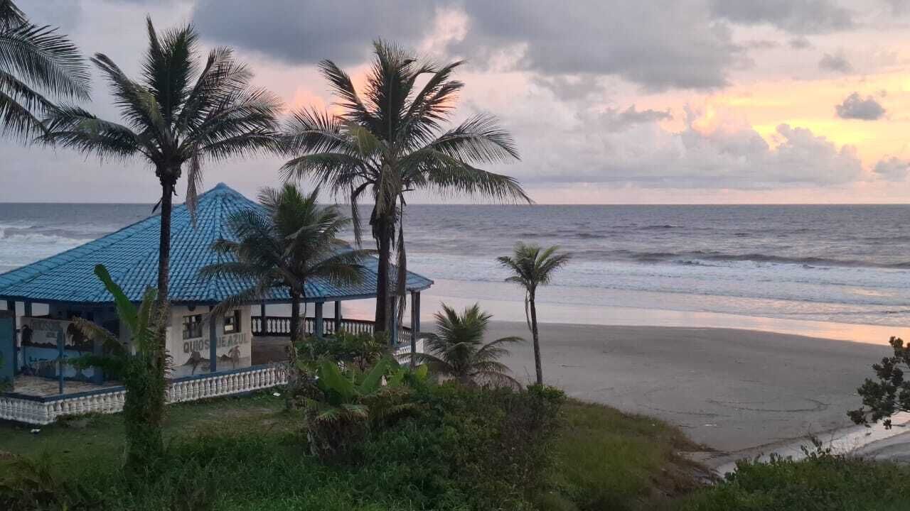 Vista de la playa con un edificio de techo azul y un área cercada.