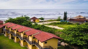 Una hilera de edificios amarillos con techos rojos, una playa y una vista despejada del océano.