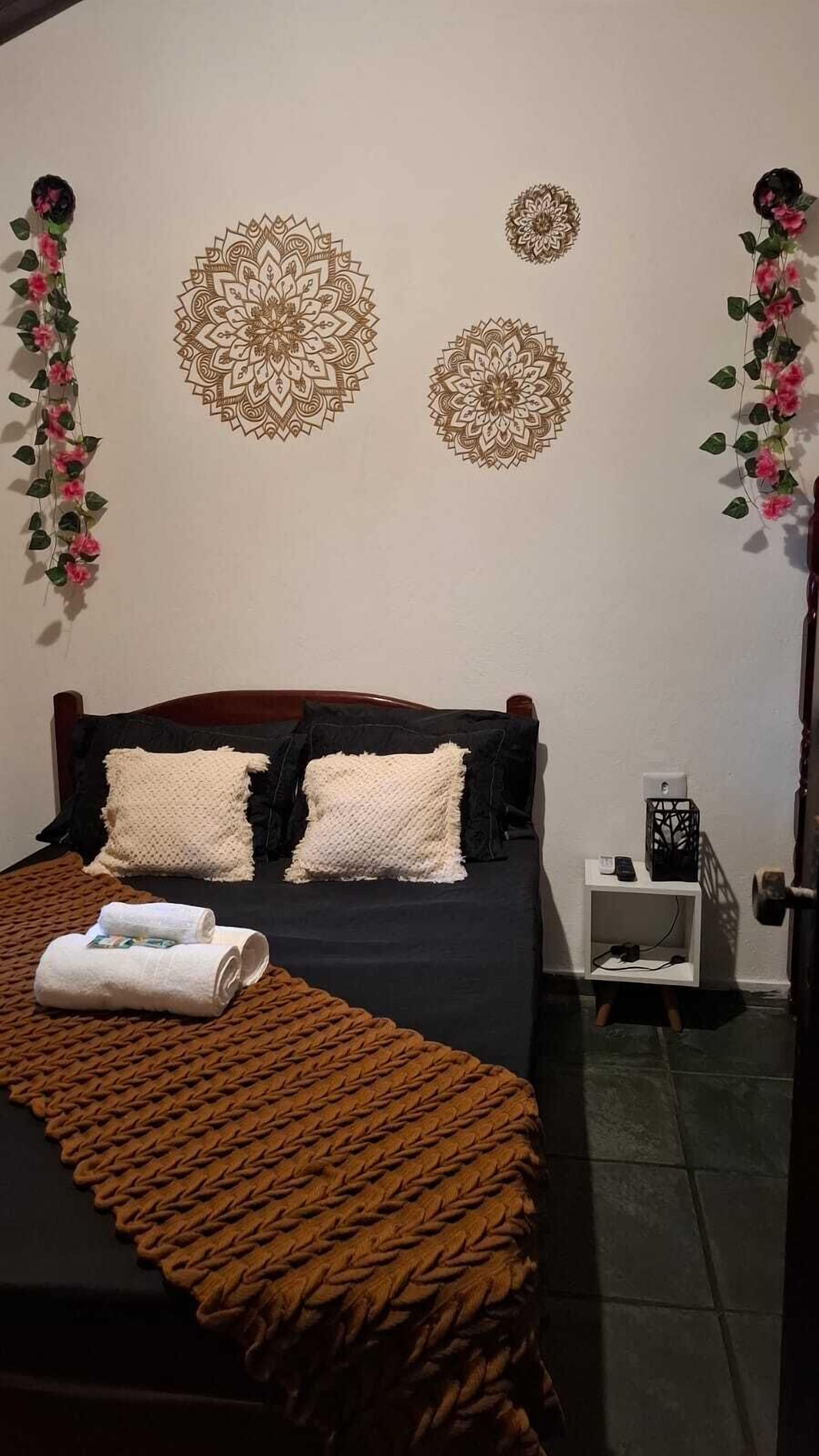 Ein Schlafzimmer mit Bett, Kissen, Decke, Nachttisch, Lampe und Wanddekoration.