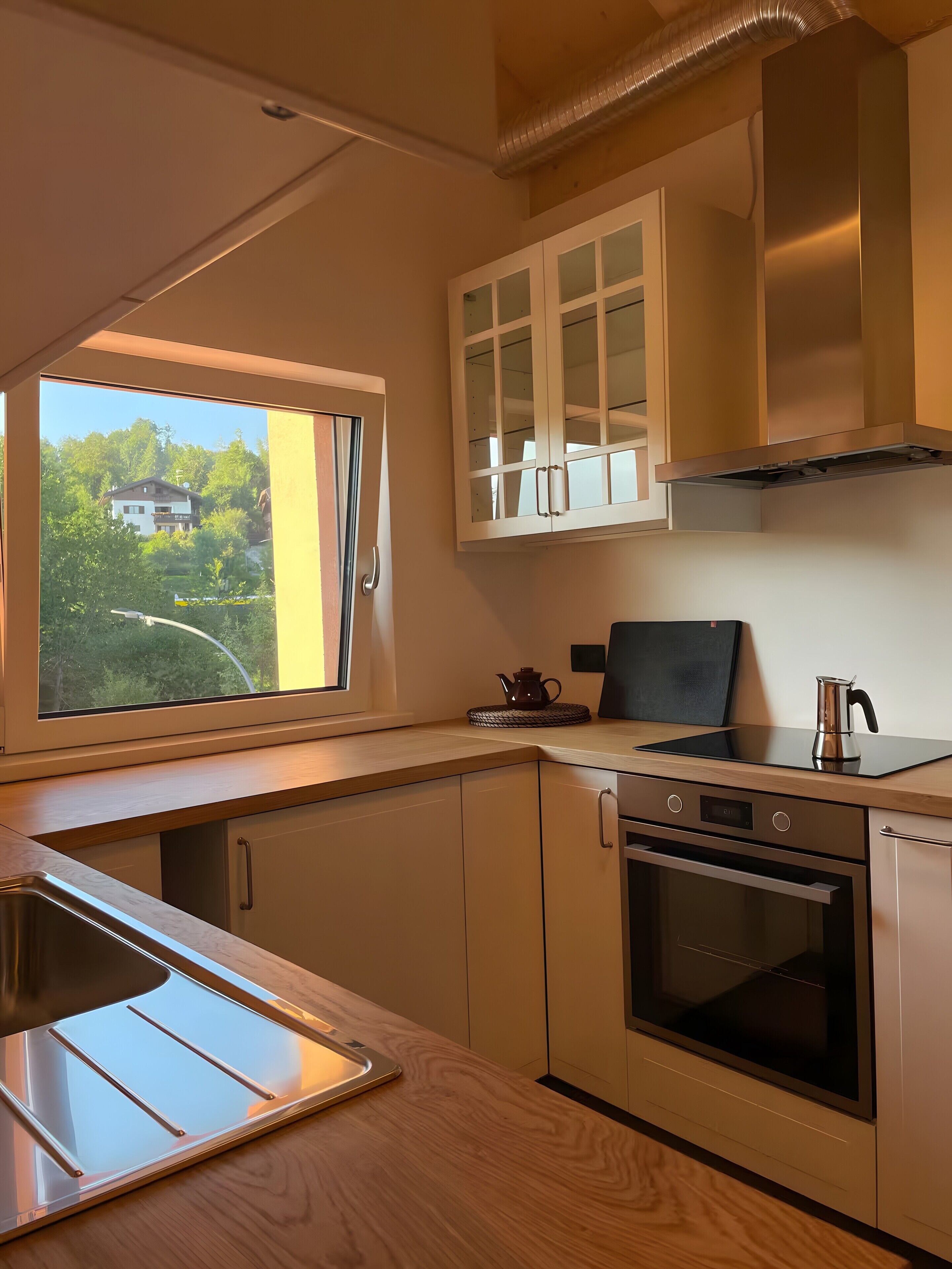 Une cuisine moderne dotée d’une fenêtre, d’appareils électroménagers en acier inoxydable et de meubles de rangement en bois.
