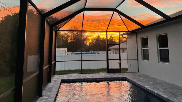Une maison moderne dotée d’un patio entièrement vitré et d’une piscine.