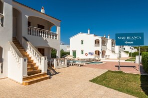 A white building with a pool, a staircase, and a sign for Mar Blanca Apartments.