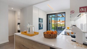 A modern kitchen with a coffee machine, a fruit bowl, and a view of the outdoors. - Villa Soligolf - Vilamoura, Algarve (Villamoura)