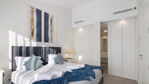 A modern bedroom with a bed, bedside tables, a nightstand, a lamp, and a wardrobe. - Villa Soligolf - Vilamoura, Algarve (Villamoura)