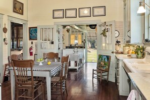 A spacious dining area with a checkered tablecloth, wooden chairs, and a view into the kitchen.