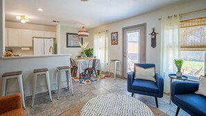 A modern kitchen with white cabinets, a dining area with a table and chairs, a blue sofa, and a ceiling fan. - AK Getaway Too ,where the waves kiss the shore and worries melt away. (Port Aransas)