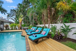 A poolside area with lounge chairs and a wooden deck.