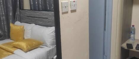 A hotel room with a bed, a mirror, a desk, and a chair.
