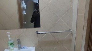 Ein kleines Badezimmer mit Waschbecken, Spiegel, Toilette und einem grünen Korb.