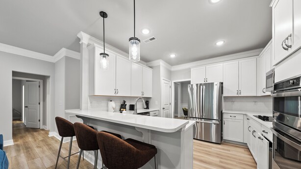 A modern kitchen with white cabinetry, stainless steel appliances, and a central island with bar stools. - Woodland Retreat at Chapel Hill (Chapel Hill)