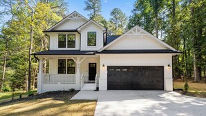 A two-story house with a garage, a covered porch, and a driveway. - Woodland Retreat at Chapel Hill (Chapel Hill)