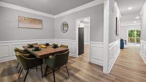 A dining area with a wooden table, green upholstered chairs, and a modern pendant light. - Woodland Retreat at Chapel Hill (Chapel Hill)