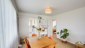 Een eethoek met een houten tafel, oranje stoelen, een hanglamp en een potplant.