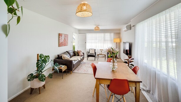 Een moderne woonkamer met een eetgedeelte, met een bank, een salontafel en een eettafel met stoelen.