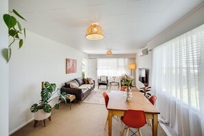 Una sala de estar moderna con zona de comedor, que incluye un sofá, una mesa de centro y una mesa de comedor con sillas.