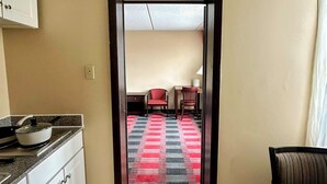A kitchen with cabinets, a countertop, and a stove. There is a hallway leading to a dining area with a checkered floor and a table. - Albany Retreat- Free Breakfast & Parking Included (Albany)