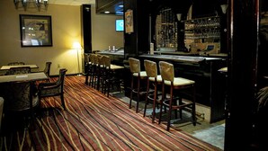 A bar area with a striped carpet, bar stools, and a counter with a wine rack. - Albany Retreat- Free Breakfast & Parking Included (Albany)