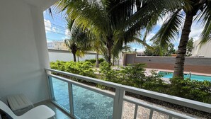 A balcony with a view of a swimming pool, surrounded by palm trees and a tiled floor. - Comfortable and modern studio (Punta Cana)