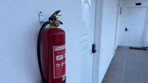 A red fire extinguisher mounted on a white wall next to a door. - Comfortable and modern studio (Punta Cana)