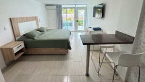 A modern hotel room with a bed, a desk, a chair, and a TV. - Comfortable and modern studio (Punta Cana)