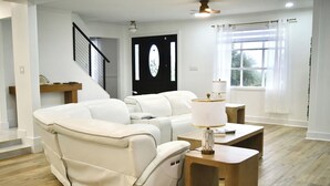 Ein modernes Wohnzimmer mit einem weißen Ledersofa, einem Holztisch und einer Lampe.