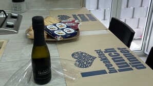 A kitchen with a bottle of wine, a tray of cheese, and a placemat with the words "breakfast lunch." - Sweet House Miracles (Napoli)