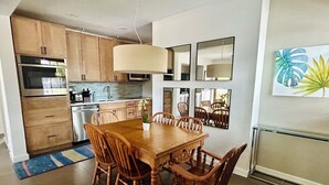 A modern kitchen with wooden cabinets, a dining table with chairs, and a large mirror on the wall. - Serendipity South: Premium Key West Pool Oasis Near The Beach (Key West)
