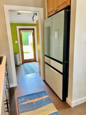 A kitchen with a refrigerator, cabinets, and a rug.