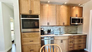 A modern kitchen with wooden cabinets, stainless steel appliances, and a tiled backsplash. - Serendipity South: Premium Key West Pool Oasis Near The Beach (Key West)