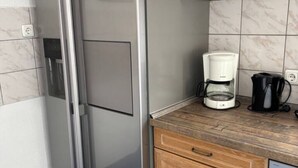 A kitchen with a refrigerator, a coffee maker, and a microwave on the counter. - Cozy vacation apartment in Aurach - peace, nature & comfort (Aurach)