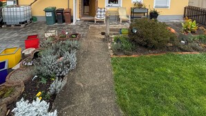 A two-story house with a balcony, a small garden, and a paved driveway. - Cozy vacation apartment in Aurach - peace, nature & comfort (Aurach)