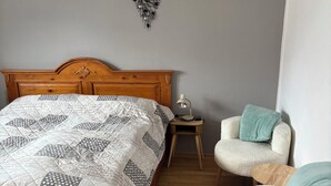 A bedroom with a wooden bed, a bedside table with a lamp, and two chairs. - Cozy vacation apartment in Aurach - peace, nature & comfort (Aurach)