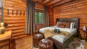 Ein Schlafzimmer in einer Blockhütte mit Bett, Fenster, Lampe und Teppich.