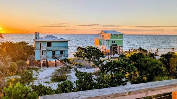 Two beachfront houses with a view of the ocean at sunset.