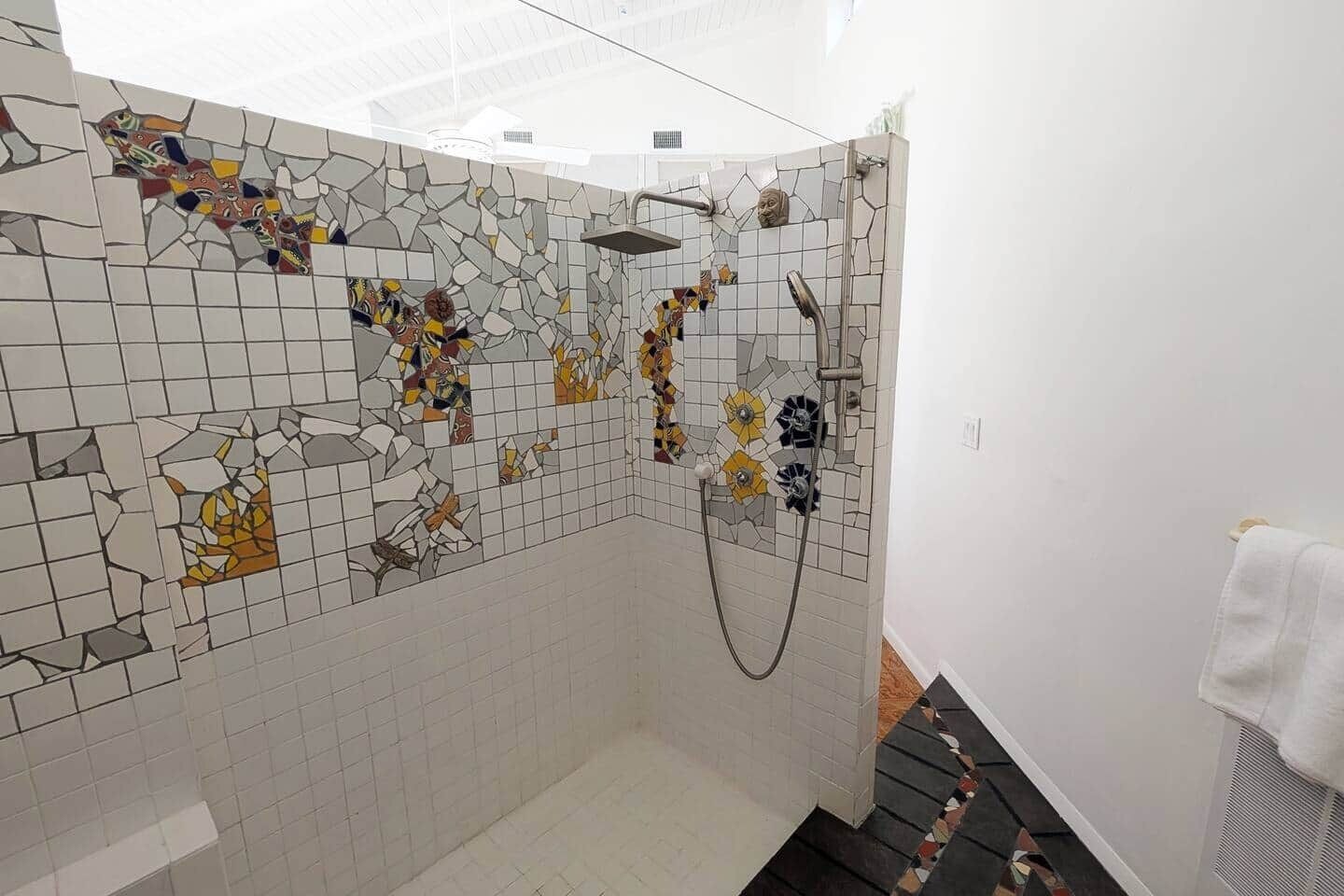 A bathroom with mosaic tile walls, a shower area, and a towel rack.