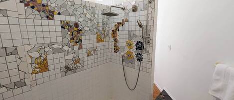 A bathroom with mosaic tile walls, a shower area, and a towel rack.