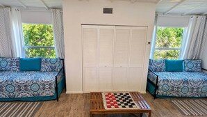 A room with two patterned sofas, a wooden coffee table with a checkered game, and a white closet with louvered doors.