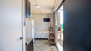 Ein schmales Dreibettzimmer mit Fernseher und einer kleinen Küchenzeile.